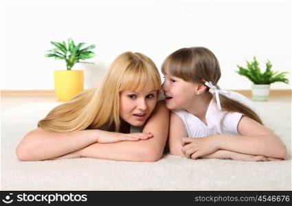 studio portrait of mother and daughter sharing a secret