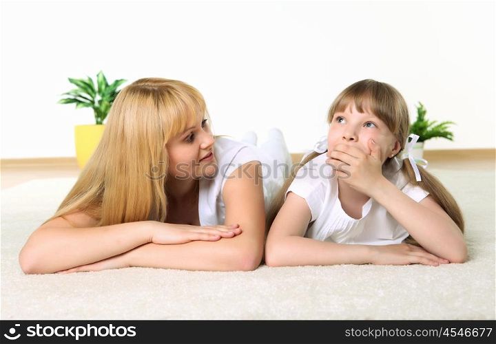 studio portrait of mother and daughter sharing a secret