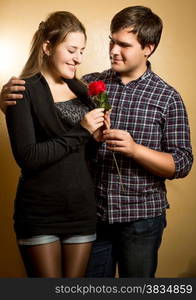 Studio portrait of smiling man giving red rose to cute girlfriend