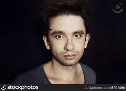 Studio portrait of young beautiful brunette guy with a stylish hair on black background