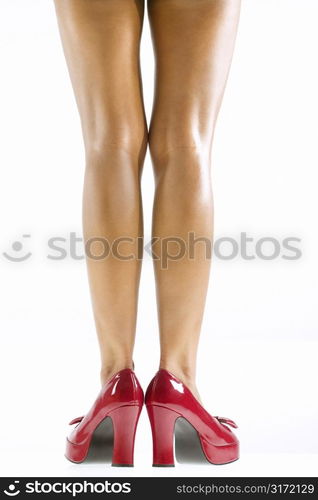 Studio portrait of young Caucasian woman&acute;s bare legs and red high heel shoes.