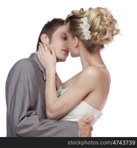 Studio portrait of young elegant enamoured just married bride and groom embracing and kissing on white background