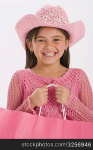 Studio portrait of young girl wearing pink cowgirl hat and carrying pink shopping bag