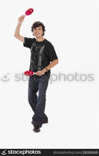 Studio portrait of young man dancing with maracas
