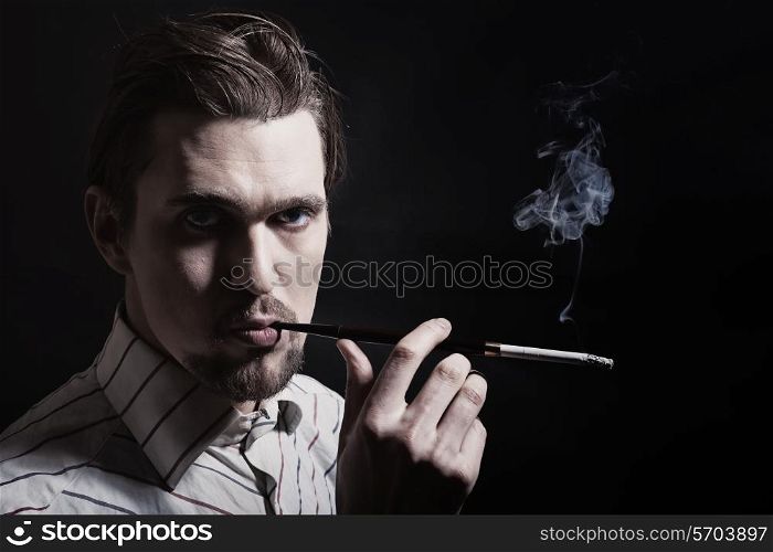 Studio portrait of young man smoking cigarette on a black background. Retor style