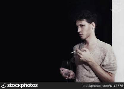 Studio portrait of young man with glass wine and cigarettes
