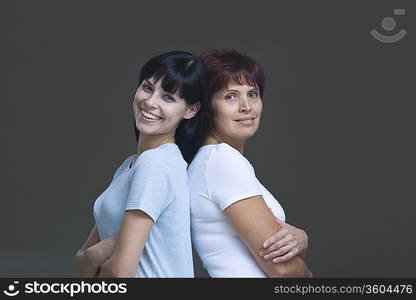 Studio portrait of young woman and mother back to back