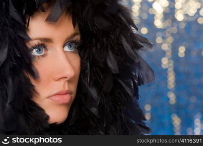 Studio portrait shot of a stunningly beautiful young blonde woman wrapped in feathers and shot with a blue reflective background