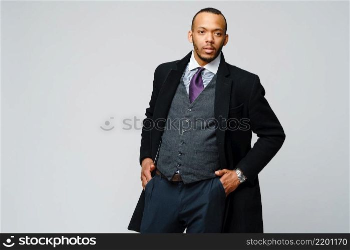 studio shot of a african-american businessman wearing coat over light grey background.. studio shot of a african-american businessman wearing coat over light grey background