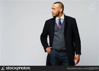 studio shot of a african-american businessman wearing coat over light grey background.. studio shot of a african-american businessman wearing coat over light grey background