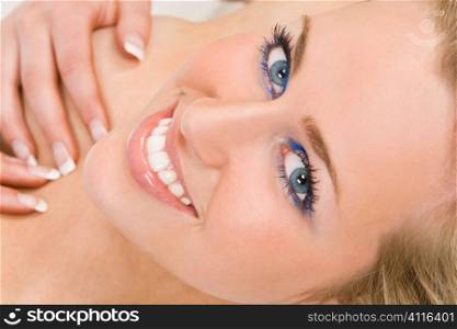 Studio shot of a beautiful blond haired blue eyed female model laying down naked but keeping covered