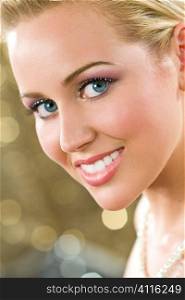 Studio shot of a beautiful blond haired blue eyed female model wearing classy make up and with a sparkling golden background