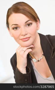 Studio shot of a beautiful young brunette woman with striking brown eyes and an enigmatic smile dressed in a smart business suit