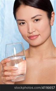 Studio shot of a beautiful young Japanese woman drinking a glass of mineral water