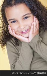 Studio shot of a beautiful young mixed race African American girl smiling and looking cheeky with hands on her face
