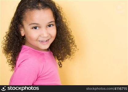 Studio shot of a beautiful young mixed race girl smiling and looking back over her shoulder