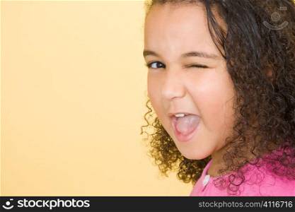 Studio shot of a beautiful young mixed race girl winking at the camera and having fun