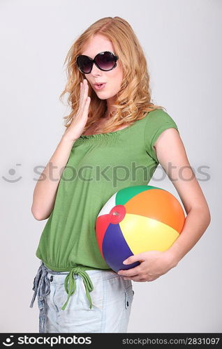 Studio shot of a cute young redhead with a beach ball