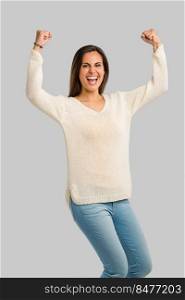 Studio shot of a happy young woman with arms raised