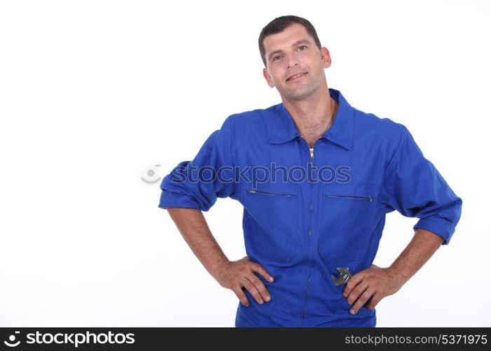 Studio shot of a man in blue overalls with his hands on his hips