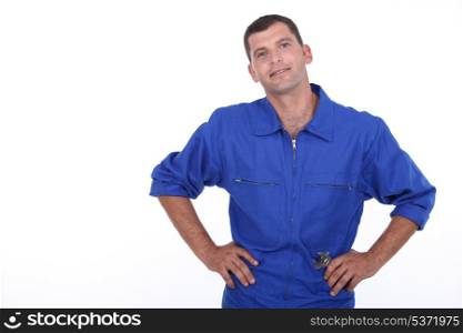Studio shot of a man in blue overalls with his hands on his hips