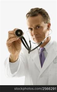 Studio shot of a mid-adult Caucasian male doctor holding out stethoscope.