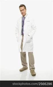 Studio shot of a mid-adult Caucasian male doctor with hands in lab coat pockets.