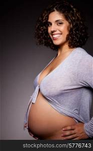 Studio shot of a pregnant woman showing her belly
