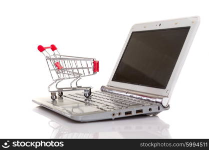 Studio shot of a shopping cart over a laptop computer