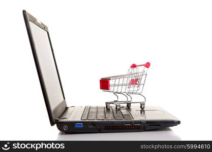 Studio shot of a shopping cart over a laptop computer