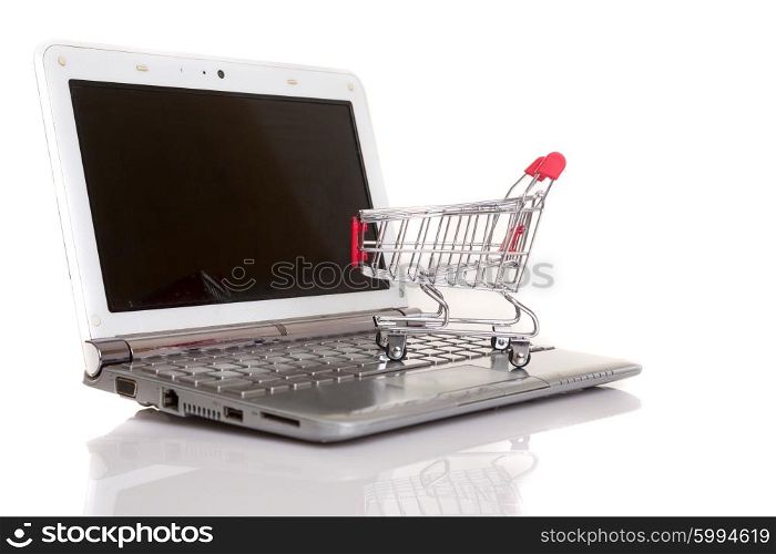 Studio shot of a shopping cart over a laptop computer