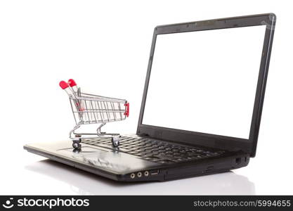 Studio shot of a shopping cart over a laptop computer