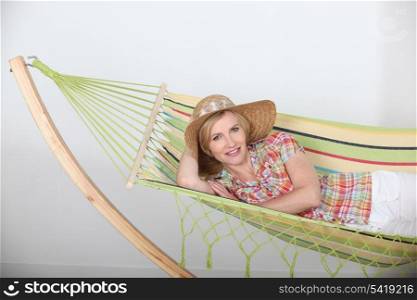Studio shot of a woman in a straw hat lounging on a striped hammock