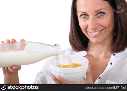 Studio shot of a woman pouring milk on her cereal