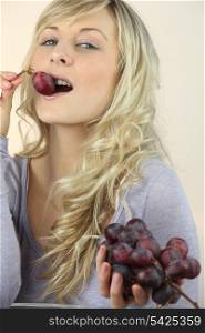 Studio shot of a young woman eating grapes