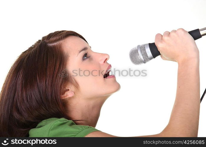 Studio shot of a young woman singing into a microphone