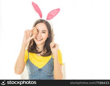 Studio shot of asian beauty happy young woman wearing bunny ears and holding up a colorful Easter egg in front of her eye lovely smile and colorful decor costume.