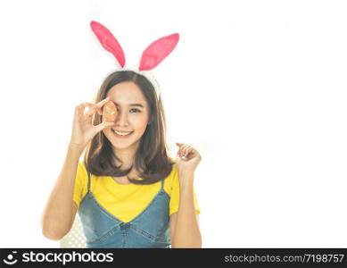 Studio shot of asian beauty happy young woman wearing bunny ears and holding up a colorful Easter egg in front of her eye lovely smile and colorful decor costume.