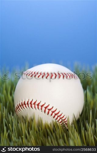 Studio shot of baseball resting in grass.