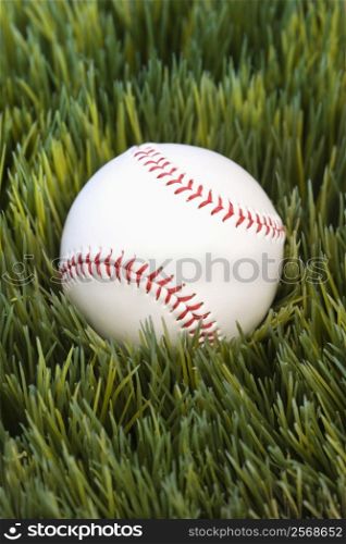 Studio shot of baseball resting in grass.