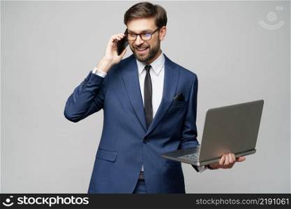 studio shot of businessman talking on the phone and holding laptop isolated over grey background. businessman talking on the phone and holding laptop isolated over grey background