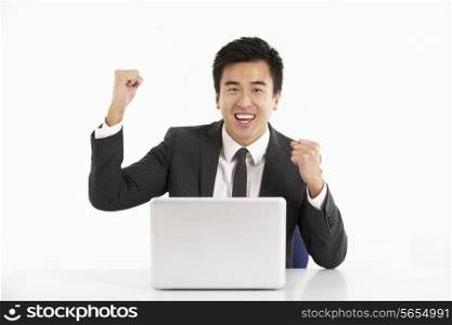 Studio Shot Of Chinese Businessman Working On Laptop And Celebrating