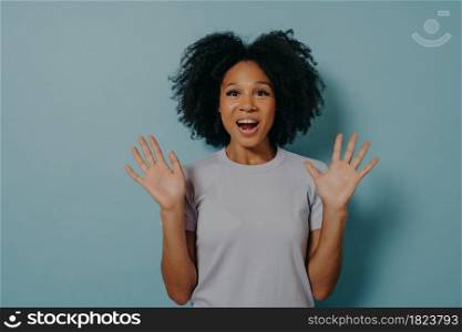 Studio shot of excited dark skinned woman showing palms at camera and demonstrating optimism, feeling happy and overjoyed while standing isolated over blue background. Positivity concept. Excited african woman showing palms and demonstrating optimism,isolated over blue background