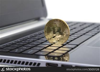 Studio shot of golden Bitcoin virtual currency on laptop. Close-up of front side.