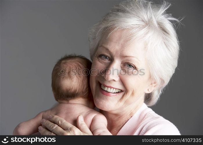 Studio Shot Of Grandmother Cuddling Granddaughter