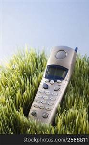 Studio shot of landline telephone placed in grass.