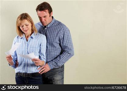 Studio Shot Of Middle Aged Couple Looking at Bills