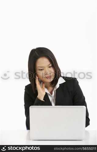 Studio Shot Of Thoughtful Chinese Businesswoman Working On Laptop
