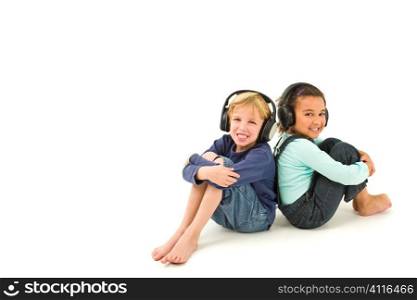 Studio shot of two children, one a blond boy the other a mixed race girl, listening to music on headphones. Isolated studio shot on a white background with a drop shadow for depth.