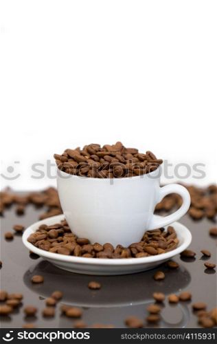 Studio shot of white cup full of and surrounded by coffee beans